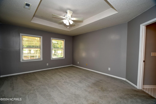 carpeted spare room with a tray ceiling, ceiling fan, and a textured ceiling