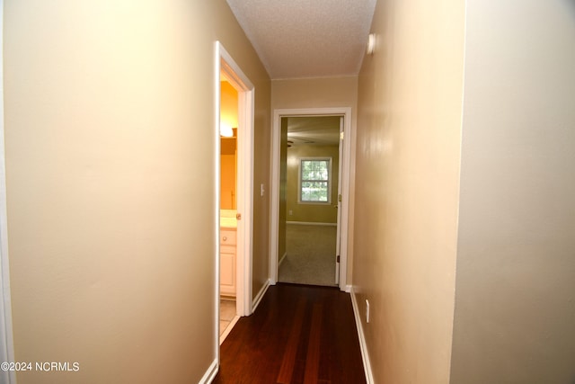 hall featuring a textured ceiling and dark wood-type flooring