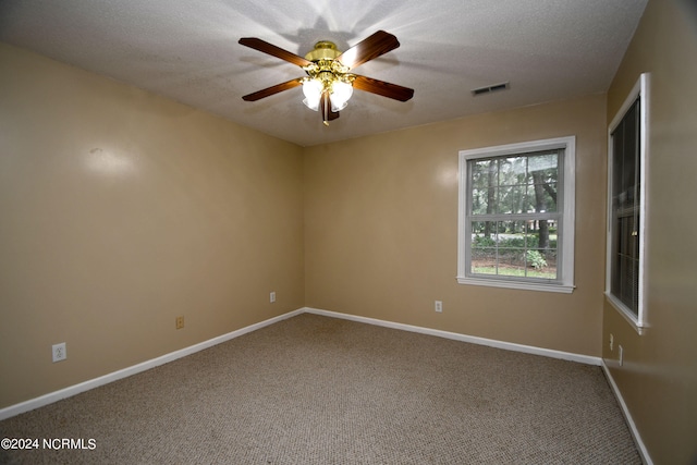 carpeted spare room featuring ceiling fan and a textured ceiling