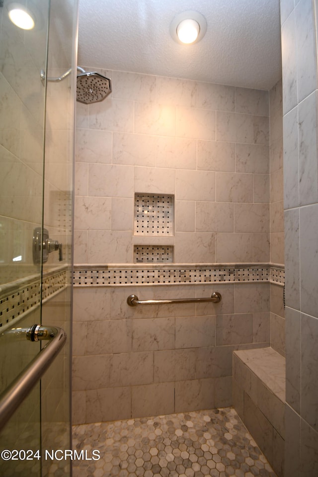 bathroom featuring a textured ceiling and walk in shower