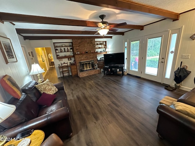 living room featuring a fireplace, beamed ceiling, dark hardwood / wood-style flooring, a textured ceiling, and ceiling fan