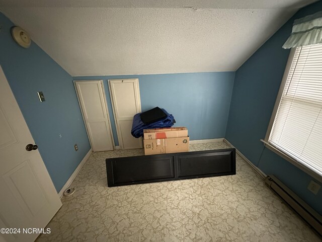 bedroom featuring lofted ceiling, a textured ceiling, and a baseboard radiator