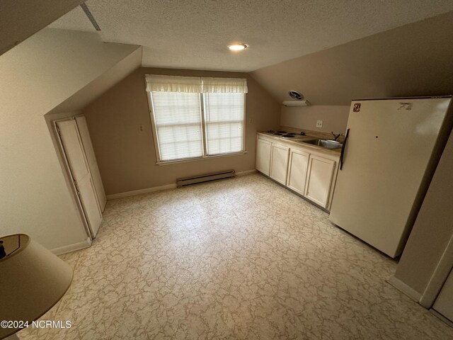 additional living space with sink, vaulted ceiling, a baseboard heating unit, and a textured ceiling