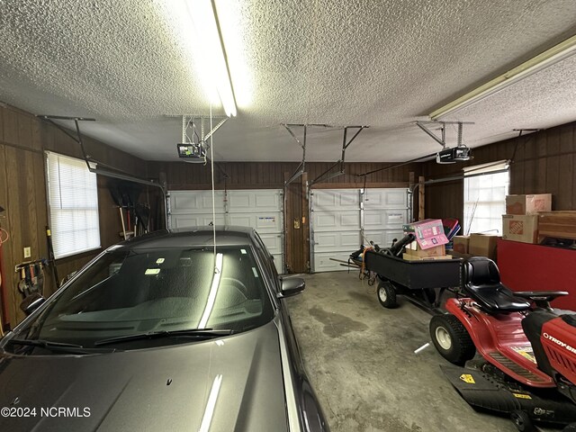 garage featuring a garage door opener and wooden walls