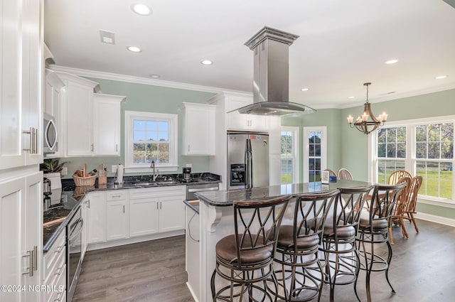 kitchen with a breakfast bar, a center island, white cabinets, range hood, and appliances with stainless steel finishes