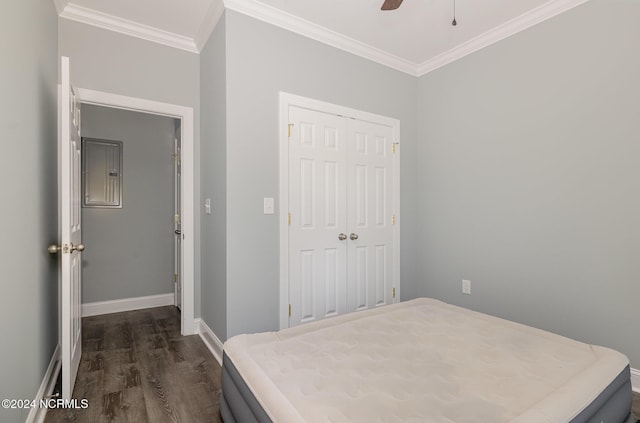 bedroom featuring ceiling fan, dark wood-type flooring, electric panel, crown molding, and a closet