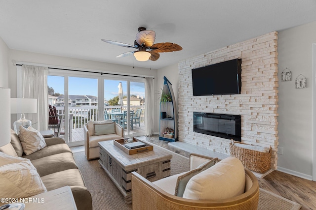 living room featuring light wood-type flooring, a fireplace, and ceiling fan