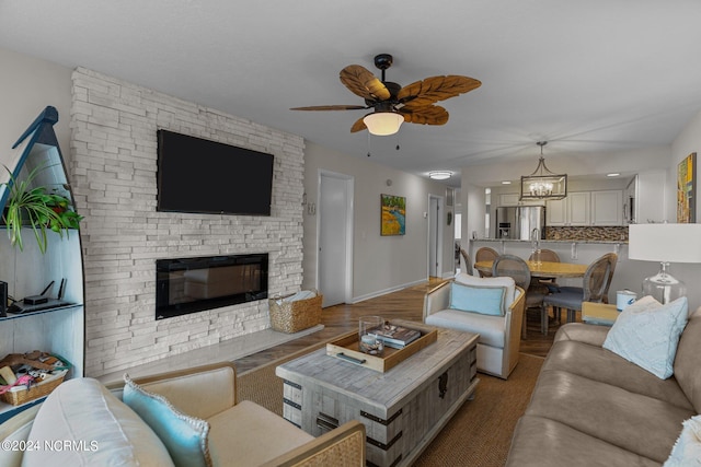 living room featuring ceiling fan with notable chandelier and a fireplace