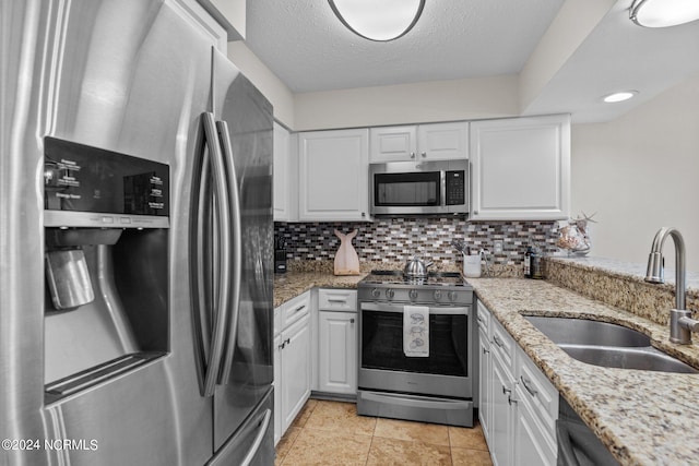 kitchen featuring white cabinetry, appliances with stainless steel finishes, light stone counters, and sink