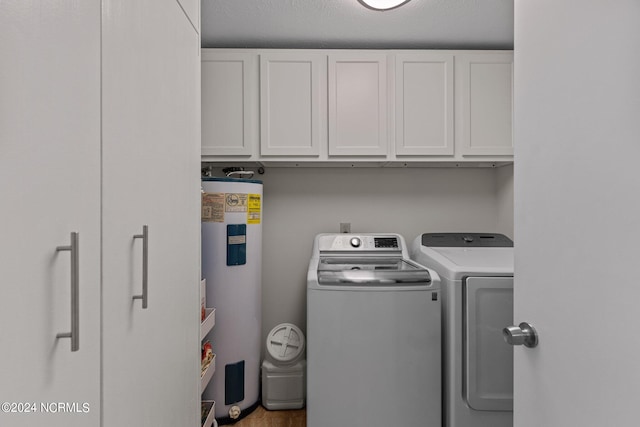 laundry room with water heater, washing machine and dryer, and cabinets