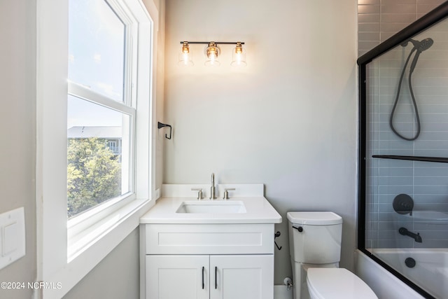 full bathroom with enclosed tub / shower combo, vanity, and toilet