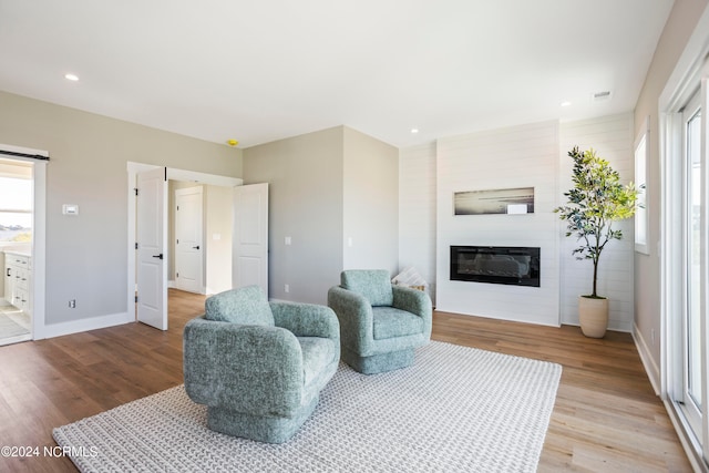 living area featuring a healthy amount of sunlight, light wood-type flooring, and a fireplace