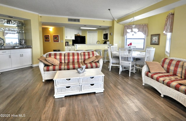 living room featuring dark wood-style floors, ornamental molding, visible vents, and a healthy amount of sunlight