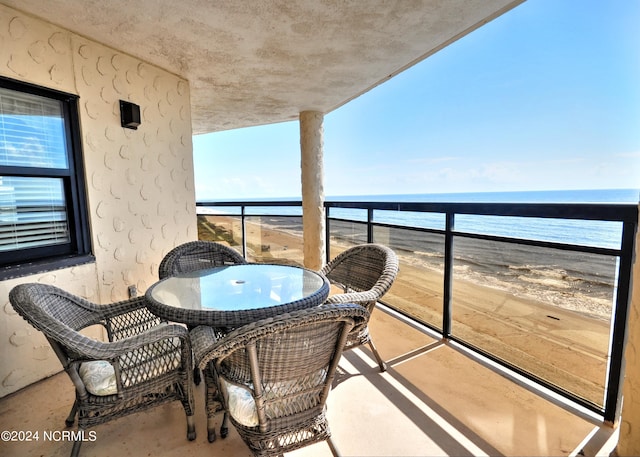 balcony featuring a water view, a sunroom, and a view of the beach