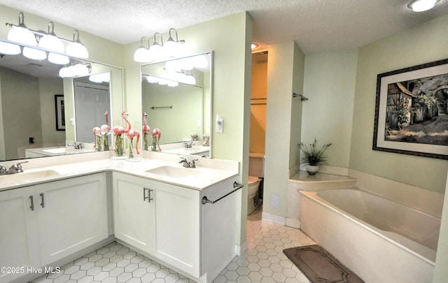 bathroom featuring a textured ceiling, a sink, toilet, and a bath