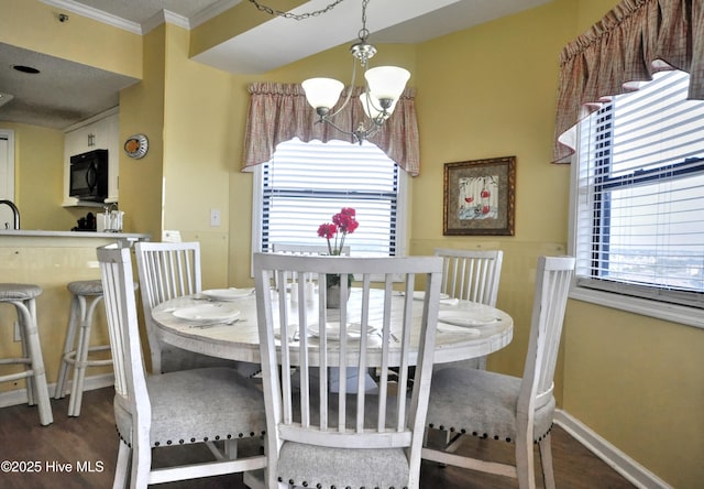 dining area featuring a notable chandelier, crown molding, baseboards, and wood finished floors