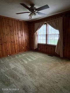 bonus room with wood walls, ceiling fan, and light colored carpet