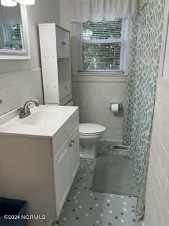 bathroom with vanity, tile walls, and toilet