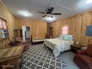 carpeted bedroom with ceiling fan, electric panel, and wooden walls