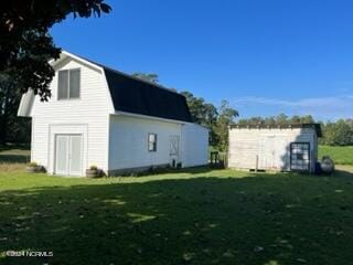 view of side of property with a lawn and an outbuilding