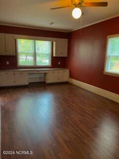 kitchen with ceiling fan, built in desk, dark wood-type flooring, white cabinetry, and crown molding