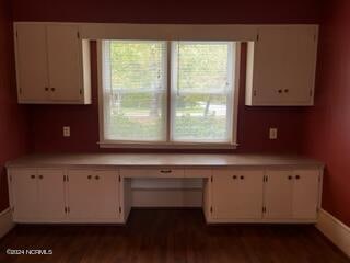 kitchen with white cabinets, built in desk, and dark hardwood / wood-style flooring