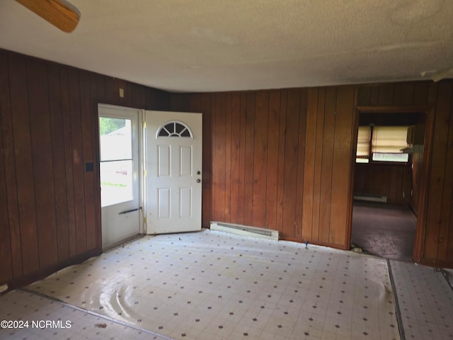 entrance foyer with wood walls, ceiling fan, and baseboard heating