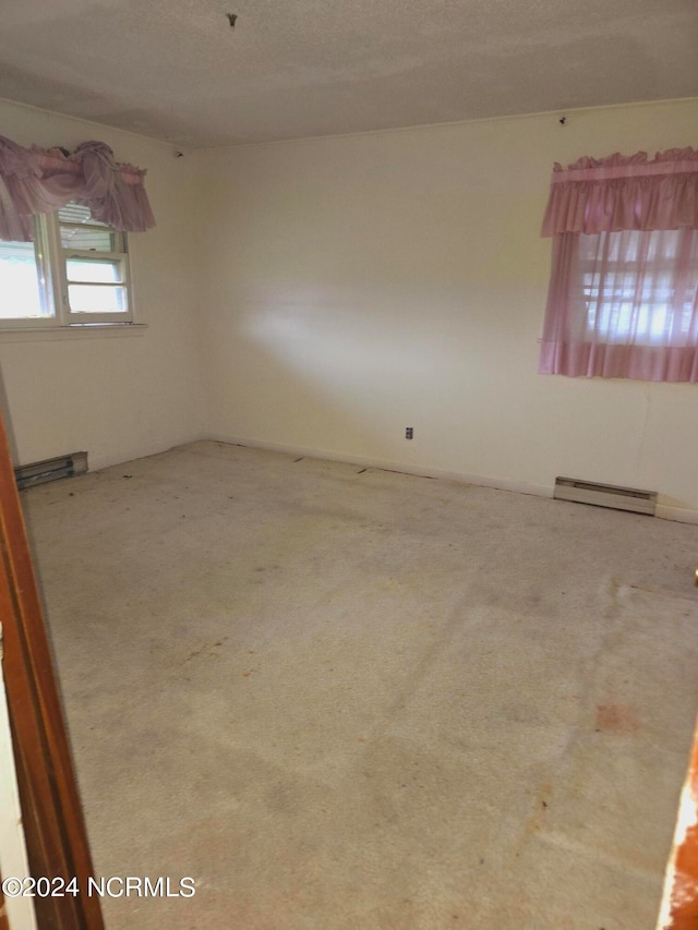 carpeted empty room with a baseboard heating unit