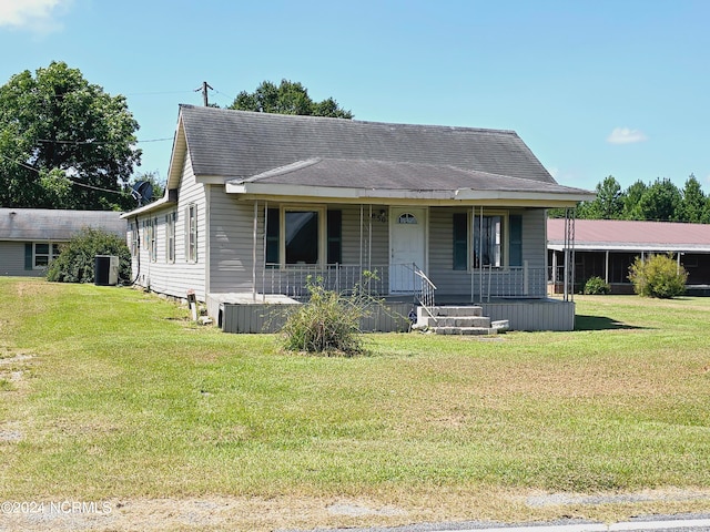 view of front of property featuring a front yard, cooling unit, and covered porch