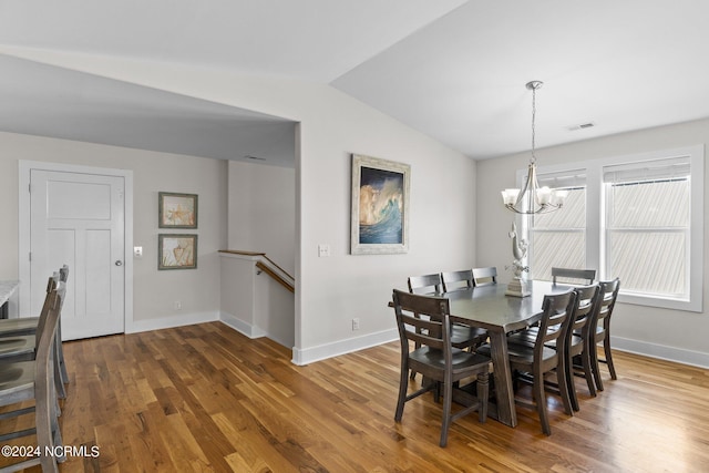 dining space with lofted ceiling, hardwood / wood-style floors, and a chandelier