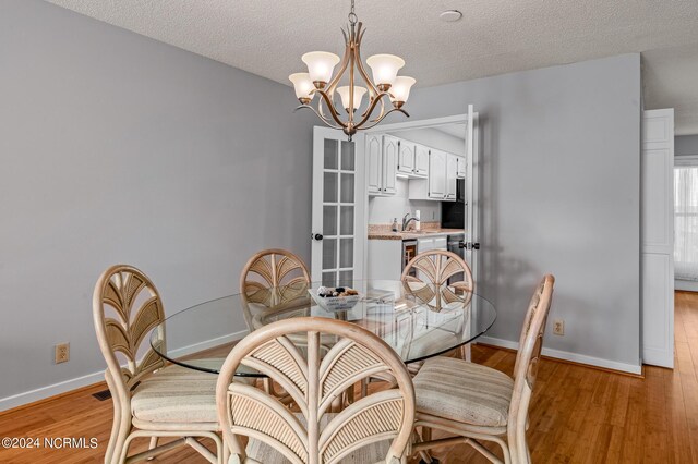 dining room featuring a textured ceiling, an inviting chandelier, and light hardwood / wood-style flooring