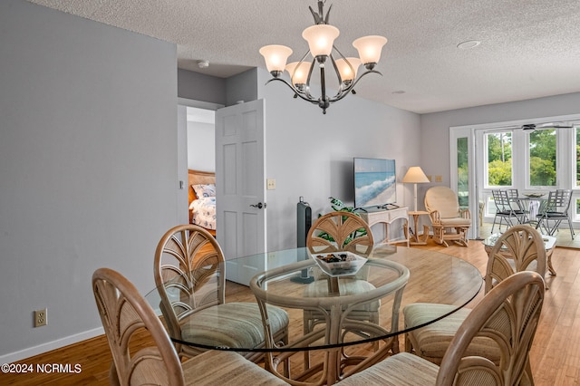 dining room with a textured ceiling, light hardwood / wood-style flooring, and a notable chandelier