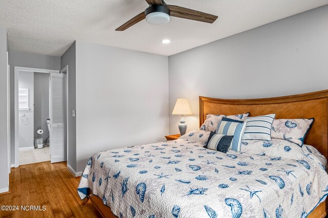 bedroom with ceiling fan, a textured ceiling, and hardwood / wood-style floors