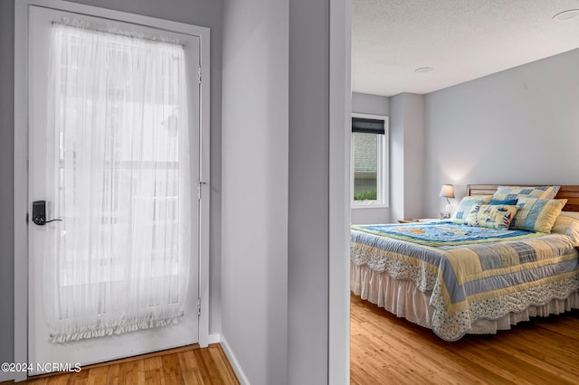 bedroom with a textured ceiling and light hardwood / wood-style flooring