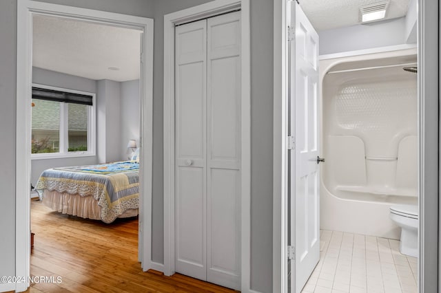 bathroom featuring wood-type flooring, a textured ceiling, a shower, and toilet