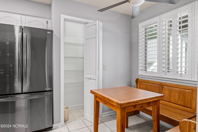 kitchen with ceiling fan, white cabinets, stainless steel fridge, and light tile patterned floors