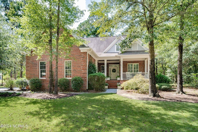 front facade featuring covered porch and a front yard