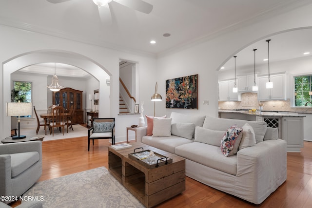 living room featuring ceiling fan, light hardwood / wood-style floors, and ornamental molding