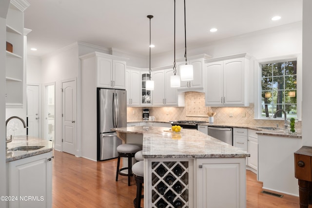 kitchen with a center island, white cabinets, sink, light hardwood / wood-style flooring, and stainless steel appliances