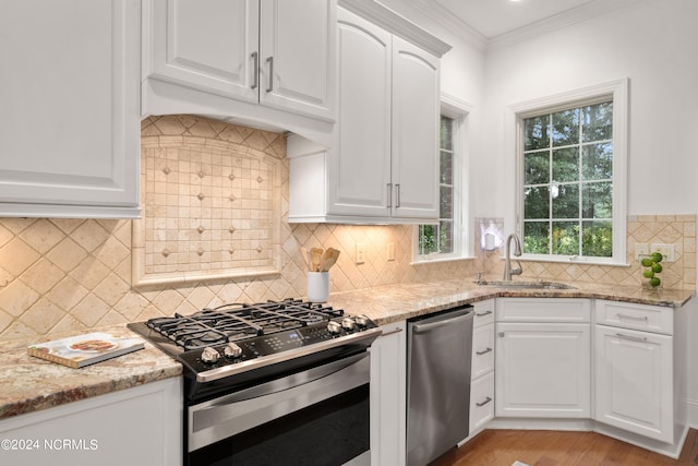 kitchen with sink, light stone counters, backsplash, white cabinets, and appliances with stainless steel finishes