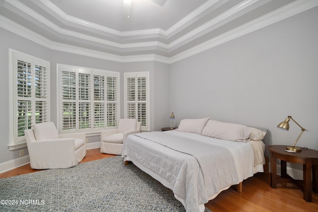 bedroom with wood-type flooring, a tray ceiling, ceiling fan, and ornamental molding