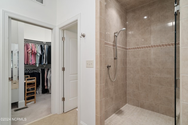 bathroom with tiled shower and tile patterned flooring