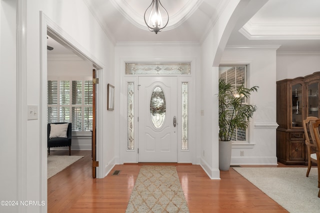 foyer featuring hardwood / wood-style flooring, ornamental molding, and a tray ceiling