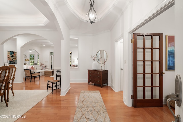 entrance foyer with ornamental molding, a tray ceiling, and light hardwood / wood-style flooring