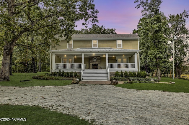 view of front of home with a front lawn, covered porch, and gravel driveway