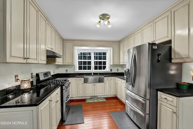 kitchen with stainless steel appliances, cream cabinets, hardwood / wood-style floors, and sink