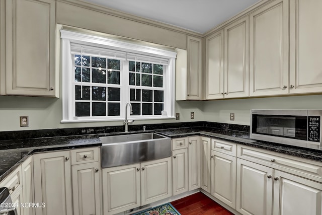 kitchen featuring stainless steel microwave, cream cabinets, visible vents, dark wood finished floors, and a sink