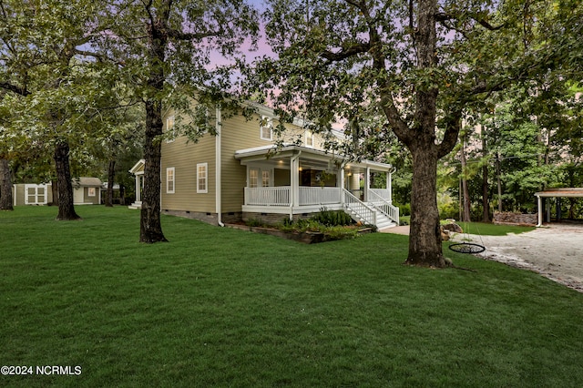 view of front of home with a carport, a porch, and a yard