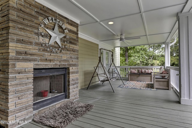 wooden terrace with ceiling fan and exterior fireplace