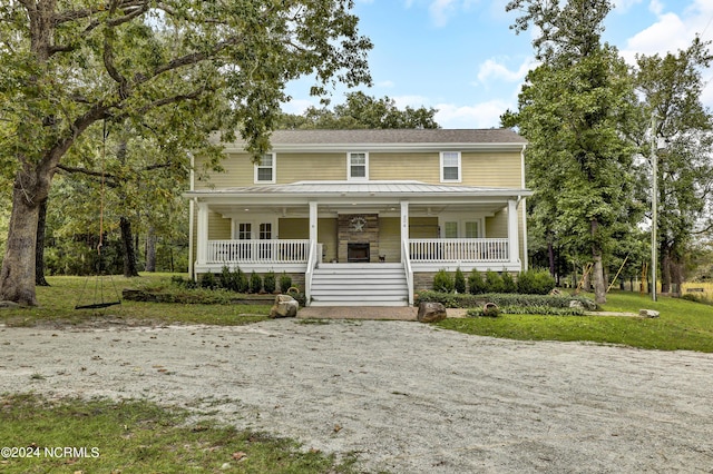 view of front facade featuring a porch, a front lawn, and gravel driveway
